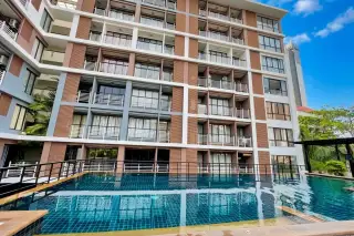 The Pride outdoor swimming pool with blue tiles reflecting the multi-story condo building with balconies and windows.