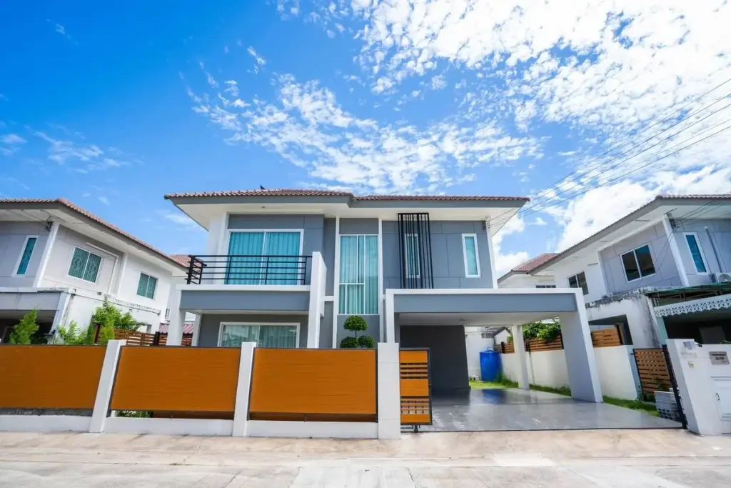 3 Bedroom House for Sale at Baan Pruksa Nara Chaiyapruek two-storey grey exterior with wooden fence and carport under blue sky