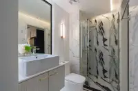 1 Bedroom Condo for Sale at Embassy Life modern bathroom with marble-tiled glass shower enclosure, vessel sink, and gold accent vanity