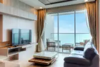 1 Bedroom Condo for Sale at Cetus Beachfront living room with leather sofa, flat-screen TV, and floor-to-ceiling ocean view windows