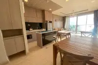 2 Bedroom Condo for Rent at Cetus Beachfront open-plan kitchen with wooden cabinets, island counter, dining table, and sea view living area