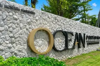 Ocean Portofino stone entrance wall with gold and black branded signage surrounded by green trees