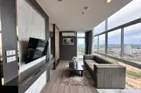 1 Bedroom Condo for Sale at The Twin Tower Jomtien Beach Pattaya living room with marble TV wall, grey sofa, and panoramic city view