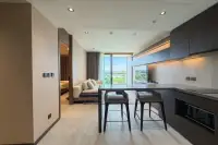 1 Bedroom Condo for Rent at Panora Estuaria kitchen counter with bar stools, dark cabinets, built-in microwave and panoramic city view window
