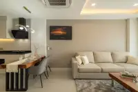 1 Bedroom Condo for Sale at Zensiri Estates and Residences dining area with wooden table, grey chairs, and open kitchen with black range hood