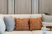 1 Bedroom Condo for Sale at Aquarous Jomtien Pattaya cream sofa with orange woven-pattern cushions against wood-panelled wall