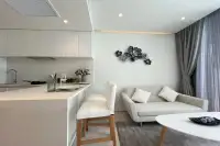 1 Bedroom Condo for Sale at Celine Wongamat white kitchen counter with bar stools, sofa, and decorative floral wall art