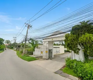 Royal Prestige gated entrance viewed from the street in Pattaya with lush greenery surroundings
