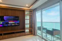 3 Bedroom Condo for Rent at Cosy Beach View living area with built-in wood TV cabinet and floor-to-ceiling sea view balcony doors