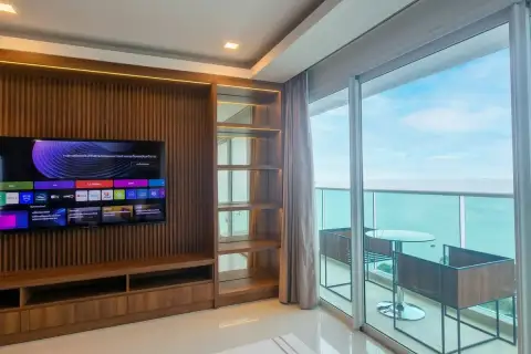 3 Bedroom Condo for Rent at Cosy Beach View living area with built-in wood TV cabinet and floor-to-ceiling sea view balcony doors