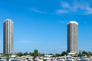 Ocean Portofino two high-rise condo towers rising above marina filled with luxury yachts under blue sky