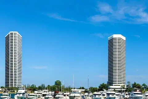 Ocean Portofino  two high-rise condo towers rising above marina filled with luxury yachts under blue sky