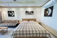 Studio Condo for Sale at Baan Suan Lalana king-size bed with plaid bedding, sofa, air conditioning unit, and decorative wall art