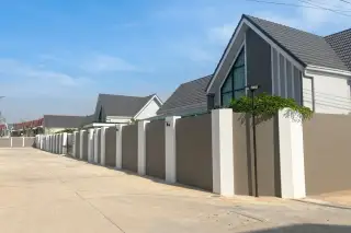 Parkside Pool Villas street view with modern grey-roofed houses and a long privacy wall.