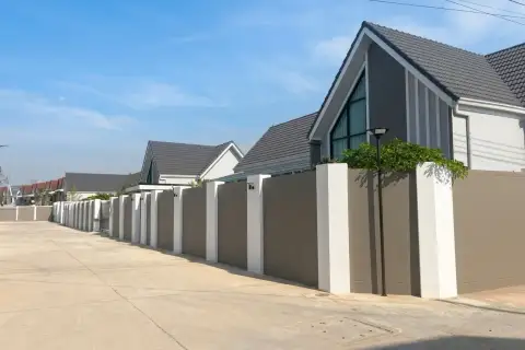 Parkside Pool Villas street view with modern grey-roofed houses and a long privacy wall.