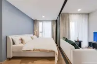 1 Bedroom Condo for Sale at Aquarous Jomtien Pattaya: Bedroom with blue accent wall, white bed, open closet, and bathroom entrance.