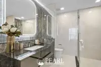 2 Bedroom Grand Executive Condo for Sale at Aquarous Jomtien Pattaya: Bathroom with black marble vanity, illuminated mirror, and shower enclosure.