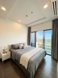 1 Bedroom Condo for Sale at Pattaya Posh bedroom with balcony access and tree-lined outdoor view
