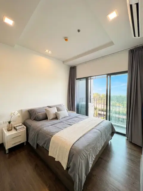 1 Bedroom Condo for Sale at Pattaya Posh bedroom with balcony access and tree-lined outdoor view