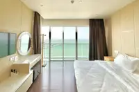 1 Bedroom Condo for Rent at Movenpick Residences bedroom with large bed, vanity, and floor-to-ceiling ocean view.