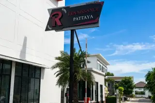 Renaissance Pattaya sign on a pole, with a palm tree, security barrier, and building entrance visible.