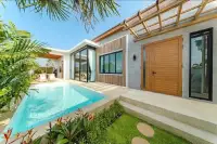 4 Bedroom House for Sale in Bang Lamung with a private swimming pool, lush greenery, and a wooden front door.