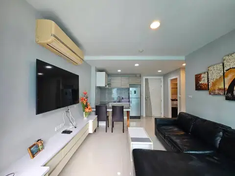 2 Bedroom Condo for Sale at Acqua Condo living room with wall-mounted TV, black leather sofa, and kitchen view