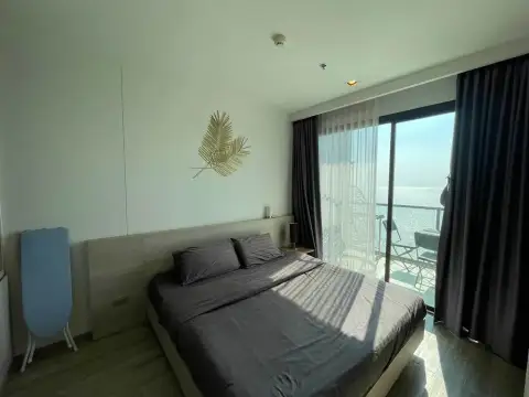 1 Bedroom Condo for Rent at Aeras bedroom with bed, palm leaf wall decor, and ocean-view balcony access