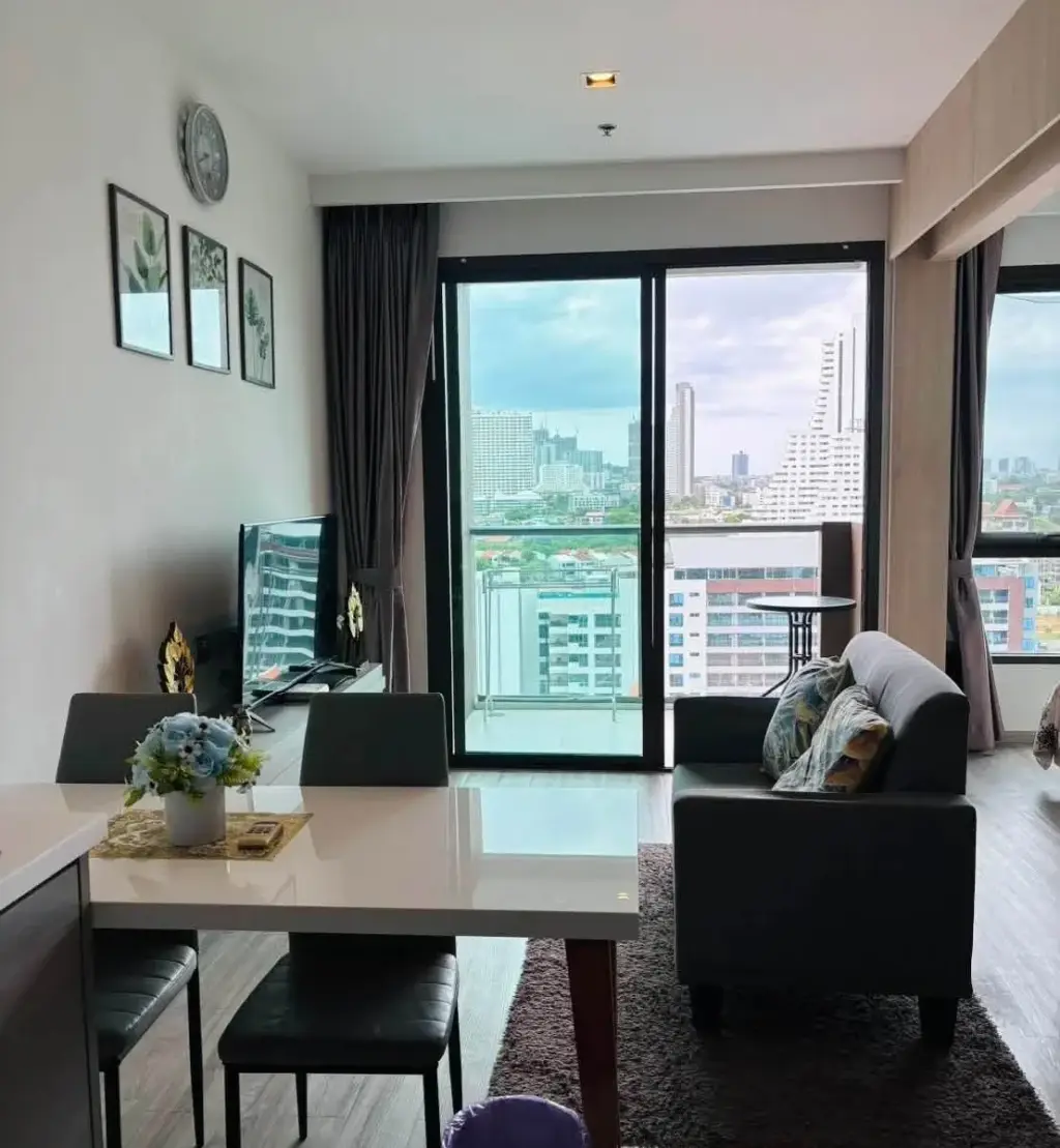 1 Bedroom Condo for Rent at Aeras living room with dining table, sofa, and balcony city skyline view