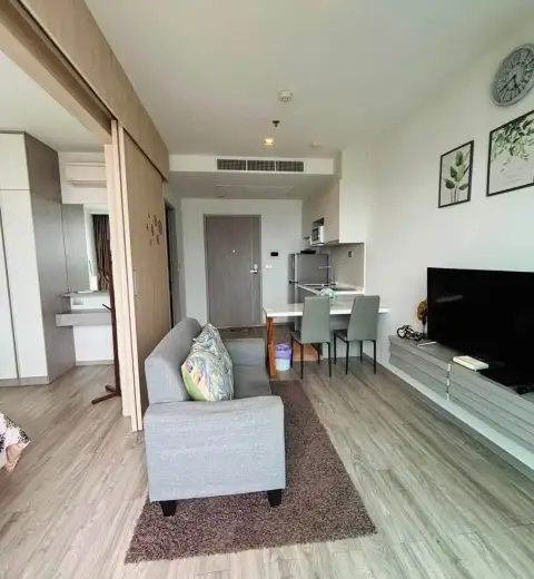 1 Bedroom Condo for Rent at Aeras open-plan living area with sofa, TV console, and kitchenette