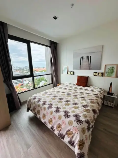 1 Bedroom Condo for Rent at Aeras bedroom with patterned bedspread and large window overlooking Pattaya