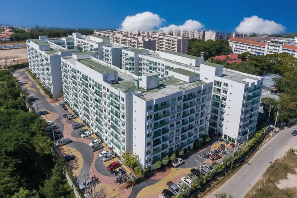 Amazon Residence aerial view of multiple white apartment buildings with green balconies and city skyline.