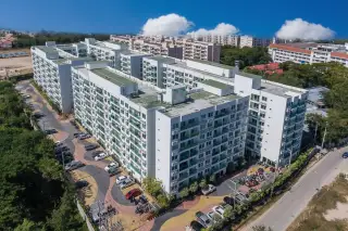 Amazon Residence aerial view of multiple white apartment buildings with green balconies and city skyline.