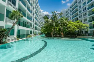 Amazon Residence winding swimming pool with palm trees and modern apartment buildings under a clear sky.