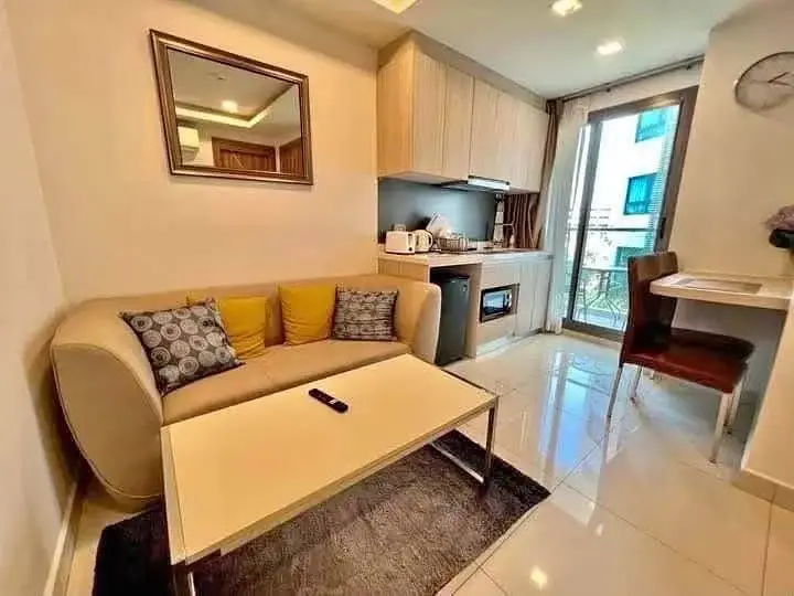 1 Bedroom Condo for Rent at Arcadia Beach Resort living room with beige sofa, kitchenette, and balcony access