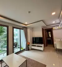 2 Bedroom Condo for Rent at Arcadia Beach Resort living area with TV stand, balcony doors, and dining table