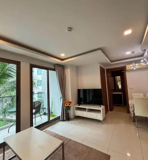 2 Bedroom Condo for Rent at Arcadia Beach Resort living area with TV stand, balcony doors, and dining table