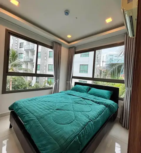2 Bedroom Condo for Rent at Arcadia Beach Resort bedroom with teal bedding and corner windows overlooking palms