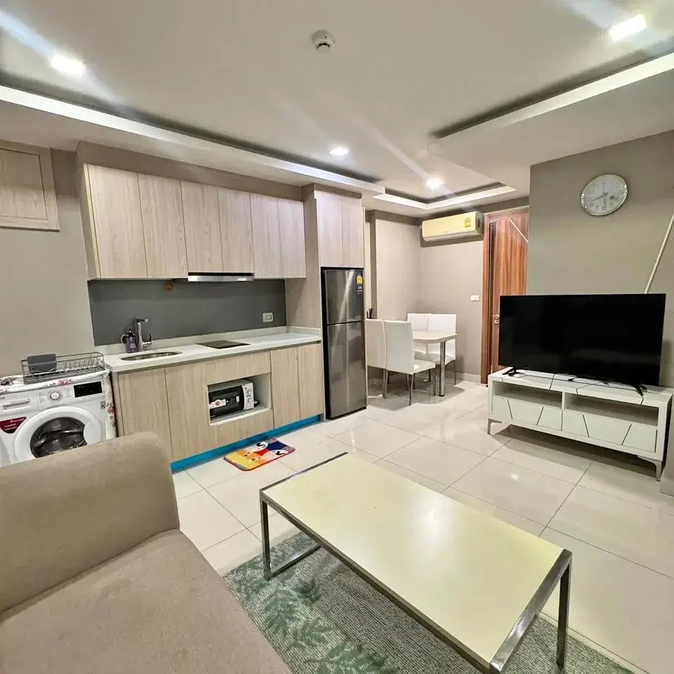 2 Bedroom Condo for Rent at Arcadia Beach Resort open-plan kitchen, dining table, and living room with flat-screen TV