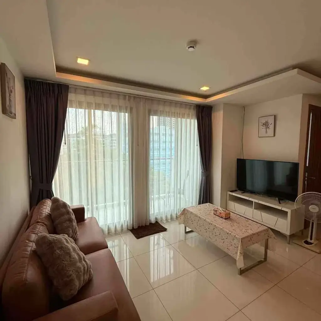 2 Bedroom Condo for Rent at Arcadia Beach Resort living room with leather sofa, TV console and balcony view