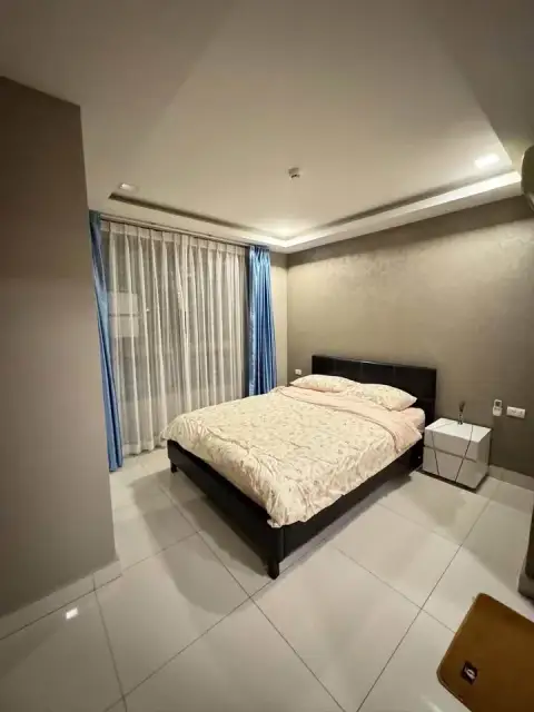 2 Bedroom Condo for Rent at Arcadia Beach Resort master bedroom with queen bed and blue curtains by window