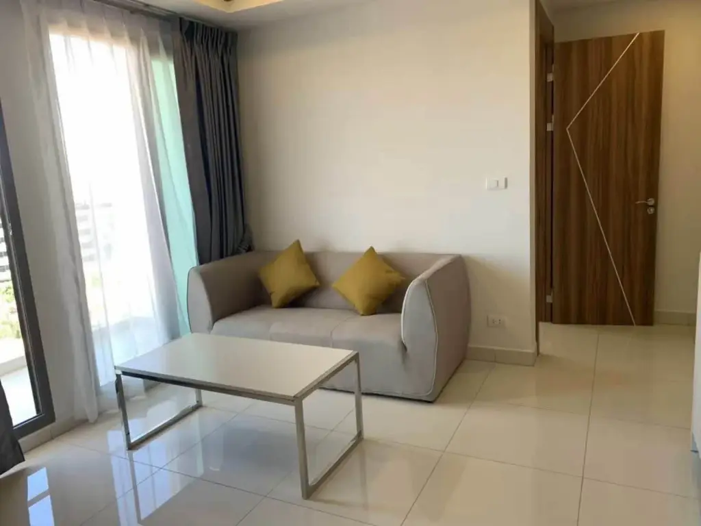 2 Bedroom Condo for Rent at Arcadia Beach Resort living room with gray sofa and balcony access