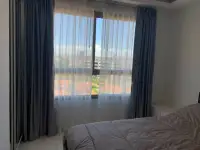 2 Bedroom Condo for Rent at Arcadia Beach Resort bedroom window with sheer curtains and rooftop view