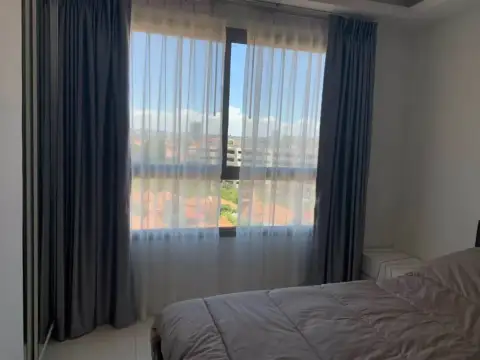 2 Bedroom Condo for Rent at Arcadia Beach Resort bedroom window with sheer curtains and rooftop view