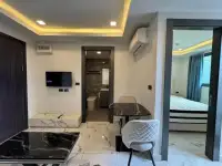 1 Bedroom Condo for Sale at Arcadia Millennium Tower open living space with TV, dining table and bedroom view