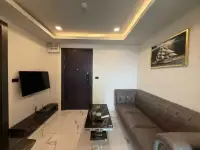1 Bedroom Condo for Rent at Arcadia Millennium Tower lounge with wall-mounted TV, sofa and entrance door