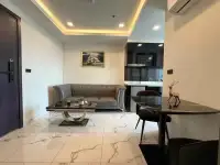 1 Bedroom Condo for Rent at Arcadia Millennium Tower living area with tufted sofa, dining table and ship painting