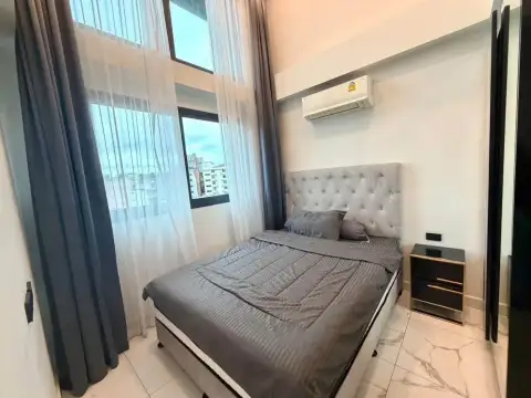 2 Bedroom Condo for Rent at Arcadia Millennium Tower bedroom with tufted headboard, double bed, and city view windows