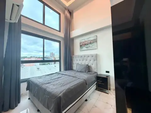 2 Bedroom Condo for Rent at Arcadia Millennium Tower second bedroom with high ceiling, artwork, and panoramic city view