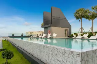Arcadia Millennium Tower rooftop infinity pool with lounge chairs and palm trees, offering panoramic city views.